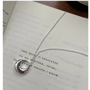 Close-up of minimalist 925 silver pendant necklace on an open book background