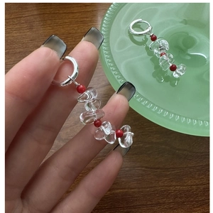 Detailed macro view of S925 silver drop earrings with clear crystals and red beads