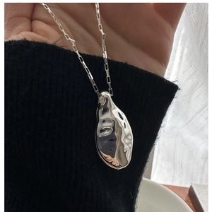 Detailed shot of S925 silver liquid metal pendant on box chain over black fabric