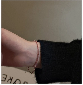 Détail d'un bracelet de perles roses délicates facettées porté sur un poignet