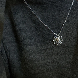 S925 sterling silver daisy flower pendant necklace on charcoal knit fabric backdrop