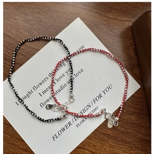 Détail de perles en argent S925 sur bracelets tressés rouges et noirs pour femmes