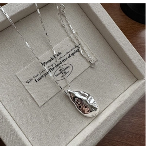 Macro detail of irregular lava texture silver pendant on a delicate box chain