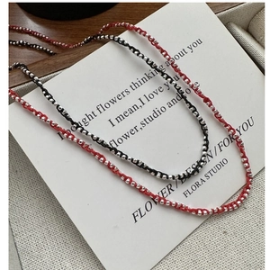 Détail macro de colliers en corde tissée avec perles en argent 925 rouge et noir