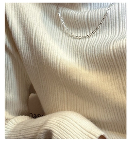 Détail du collier à maillons carrés en argent porté sur un pull en maille blanc rayé