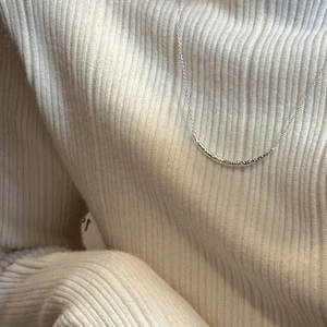Collier sourire en argent 925 avec pendentif texturé sur un pull en tricot blanc