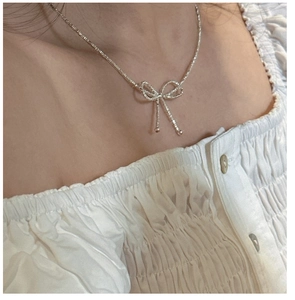 Close-up of a delicate S925 silver bow pendant necklace on a model's neck