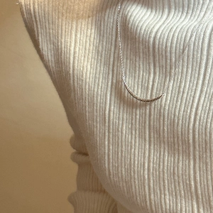 Collier sourire minimaliste en argent 925 porté sur un pull en maille côtelée