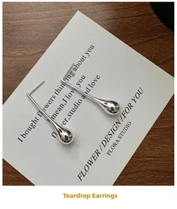 Close-up of polished S925 sterling silver teardrop earrings on a poetic card background