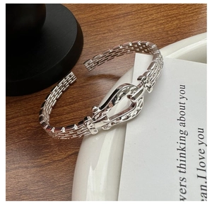 Detailed macro of textured silver horseshoe buckle bangle with braided pattern