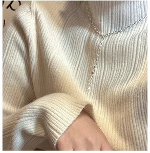 Détail du collier chaîne géométrique en argent S925 sur un pull blanc à col roulé