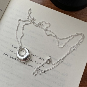 Polished 925 sterling silver minimalist pendant necklace on an open book background