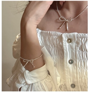 Detail of S925 sterling silver bow knot necklace and bracelet set on female model
