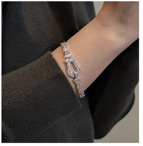 Close-up of S925 sterling silver horseshoe bangle with woven texture on a female wrist