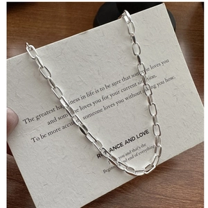 Détail d'un collier chaîne à maillons ovales en argent S925 sur une carte vintage