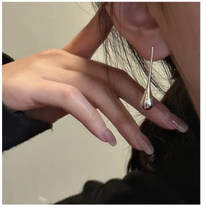 Macro view of S925 sterling silver waterdrop earrings on model showing mirror finish