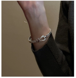 Macro detail of silver horseshoe buckle with dense woven texture on a minimalist bangle