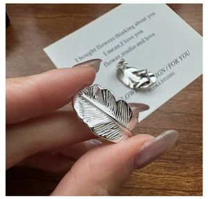 Macro detail of leaf-shaped silver stud earrings showing brushed metal texture and veins