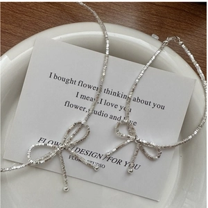 Macro detail of S925 sterling silver bow necklace with fine granular metallic texture