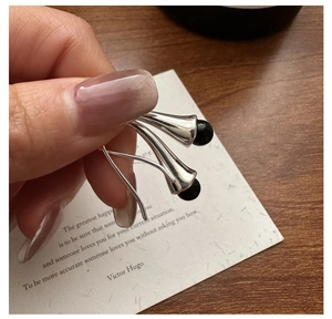 Detailed close-up of S925 silver lily-of-the-valley earrings with black pearl accents