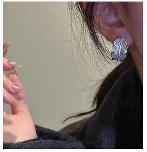 Close-up of S925 silver feather earring with vintage texture on a model ear