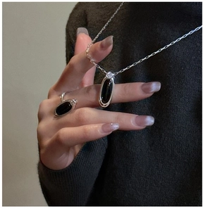 Dettaglio di set collana e anello in argento con agate nere indossati sulla mano
