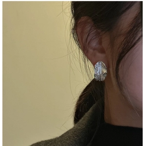Close-up of S925 silver feather earring showing intricate leaf veins on the model's ear