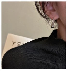 Close-up of minimalist S925 sterling silver hook earrings with a black bead on a model