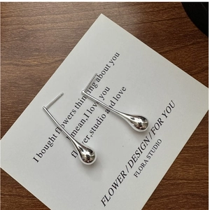 Macro detail of minimalist S925 sterling silver teardrop earrings on a white card