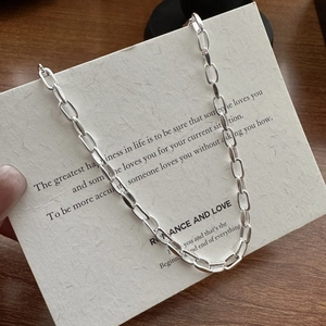 Collier minimaliste en argent S925 à maillons trombone sur une carte de citation