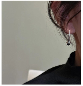 Close-up of minimalist S925 silver curved hook earrings with a sleek black bead drop