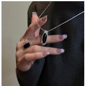 Detail of silver S925 necklace and ring set featuring oval black agate stone on model