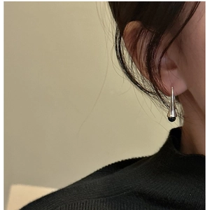 Detail of S925 sterling silver cone drop earring with black bead on a model ear