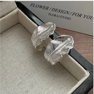 Close-up of S925 sterling silver feather earrings with detailed brushed texture finish