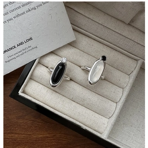 Detail of S925 silver rings with oval black and white chalcedony on a beige tray