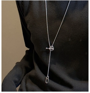 Dettaglio della collana lunga a Y argento con chiusura a T su maglione nero