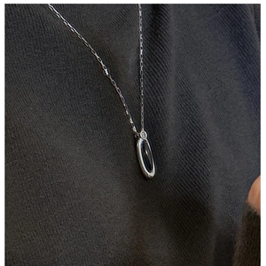 Dettaglio della collana in argento S925 con pendente in agata nera su maglia scura