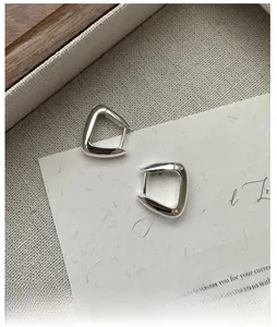 Gros plan de boucles d'oreilles carrées argentées sur un papier texturé vintage