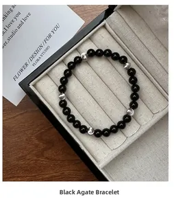Detail of black agate bracelet with silver beads displayed in a beige jewelry box