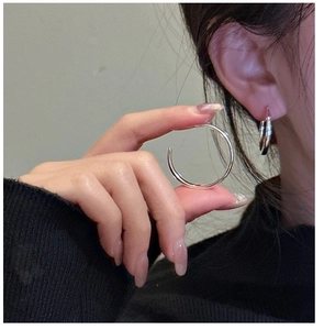 Close-up of polished S925 sterling silver hoop earrings shown on a model for size