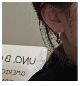 Close-up of polished S925 sterling silver hoop earring worn on ear for minimalist style