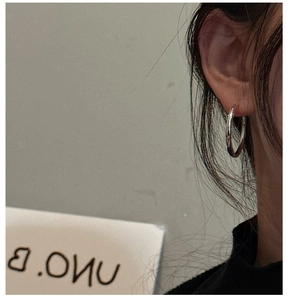 Close-up of minimalist S925 sterling silver hoop earring worn on a female ear lobe