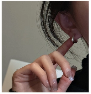 Gros plan de boucles d'oreilles argentées géométriques portées par un mannequin chic