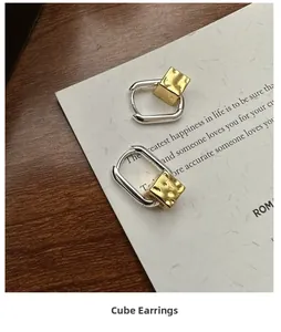 Detailed macro of S925 silver U-shape hoop earrings with hammered gold square charms