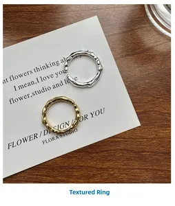 Detail showing gold and silver textured open rings on a stylish white prop card