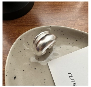 Detailed close-up of wide matte silver adjustable ring on minimalist ceramic tray