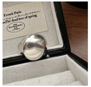 Detailed shot of a matte S925 silver round disc ring on a linen jewelry box display