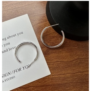 Minimalist S925 sterling silver hoop earrings shown on a rustic wooden surface