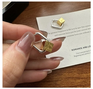 Detail of S925 silver square earrings with hammered gold charm and bicolor finish