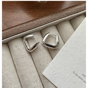 Détail de boucles d'oreilles carrées en argent avec poinçon S925 sur un présentoir